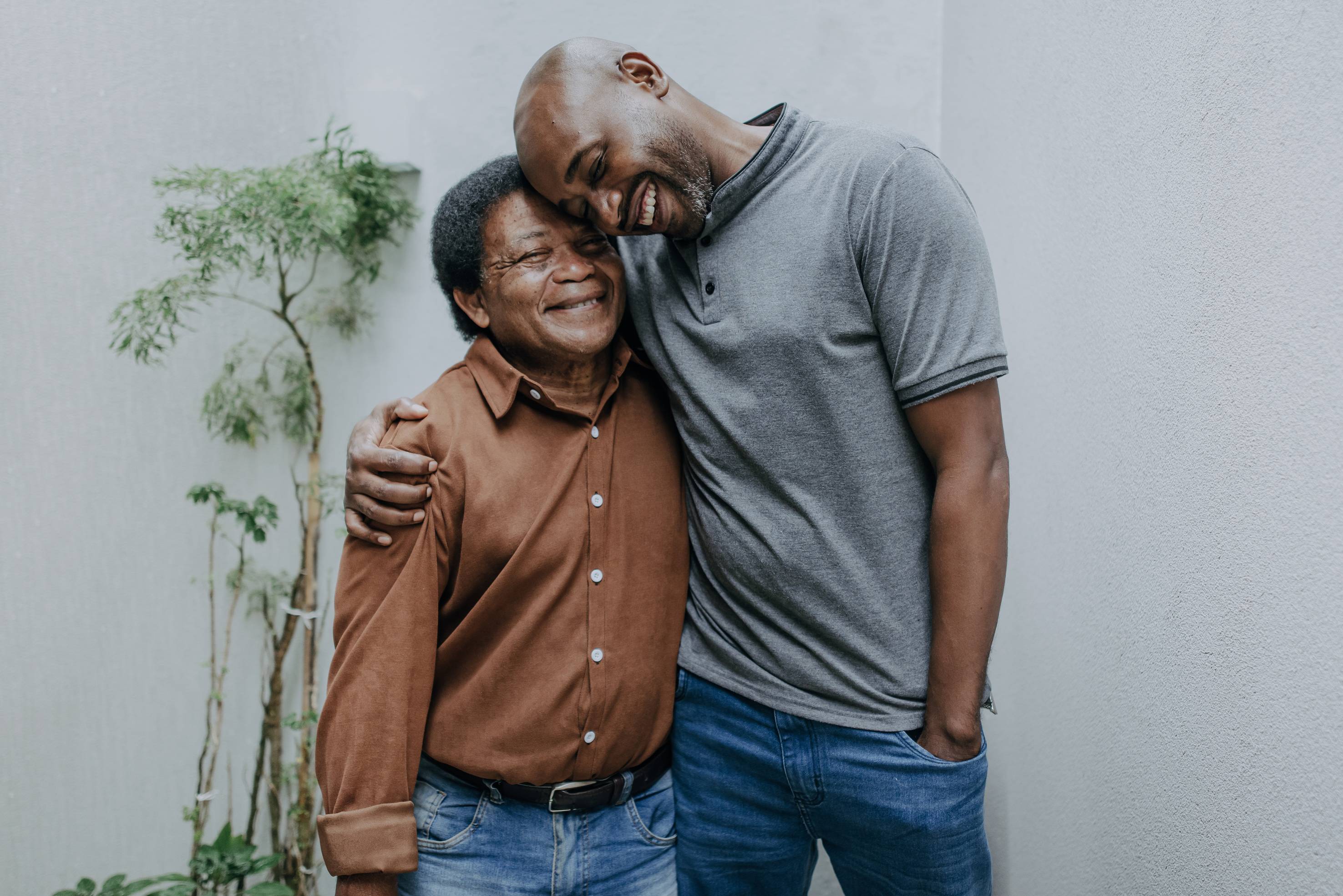 African American father and adult son embracing and smiling together