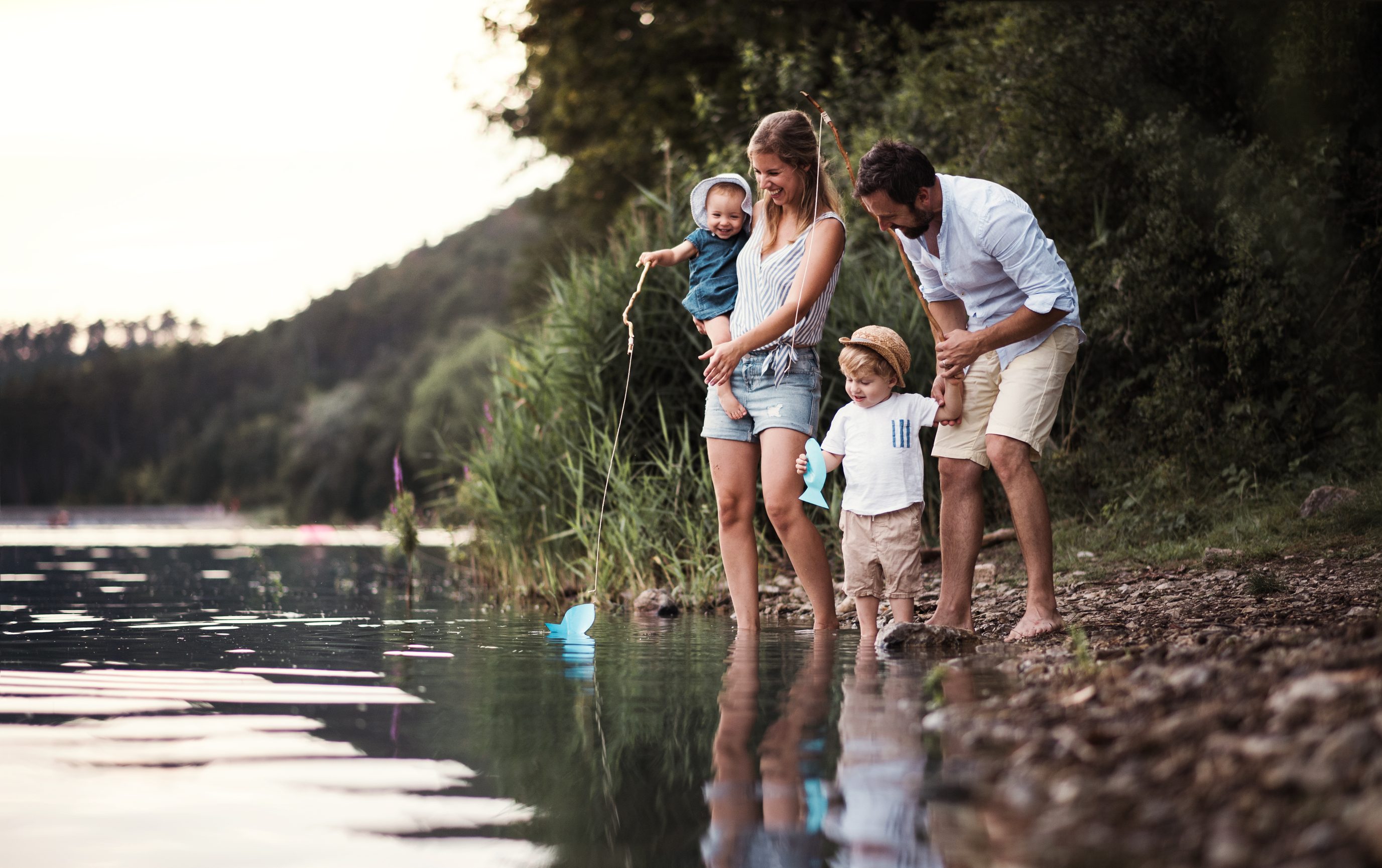 Family fishing together at lake shore during golden hour