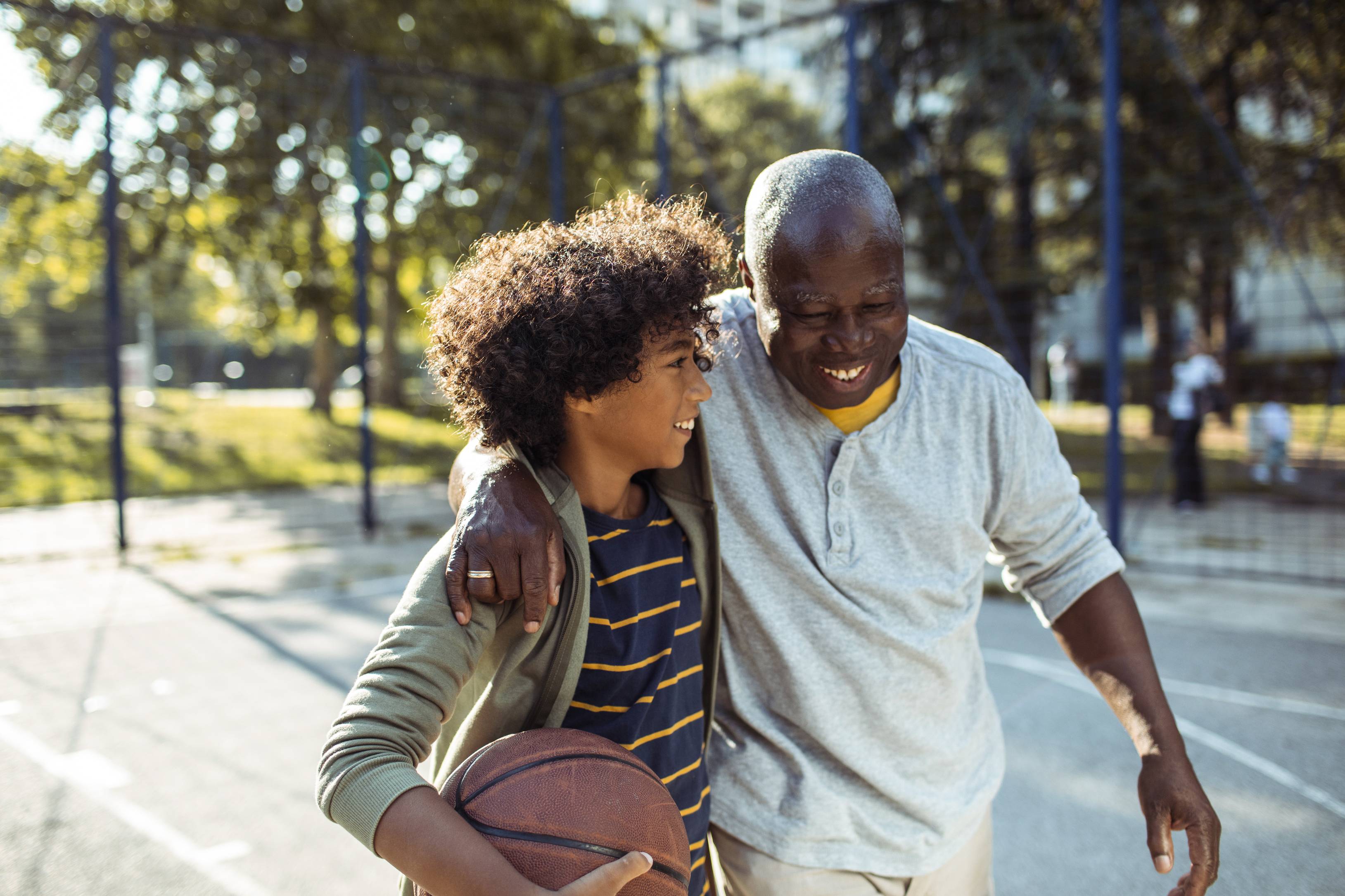 Father and son playing basketball together on outdoor court