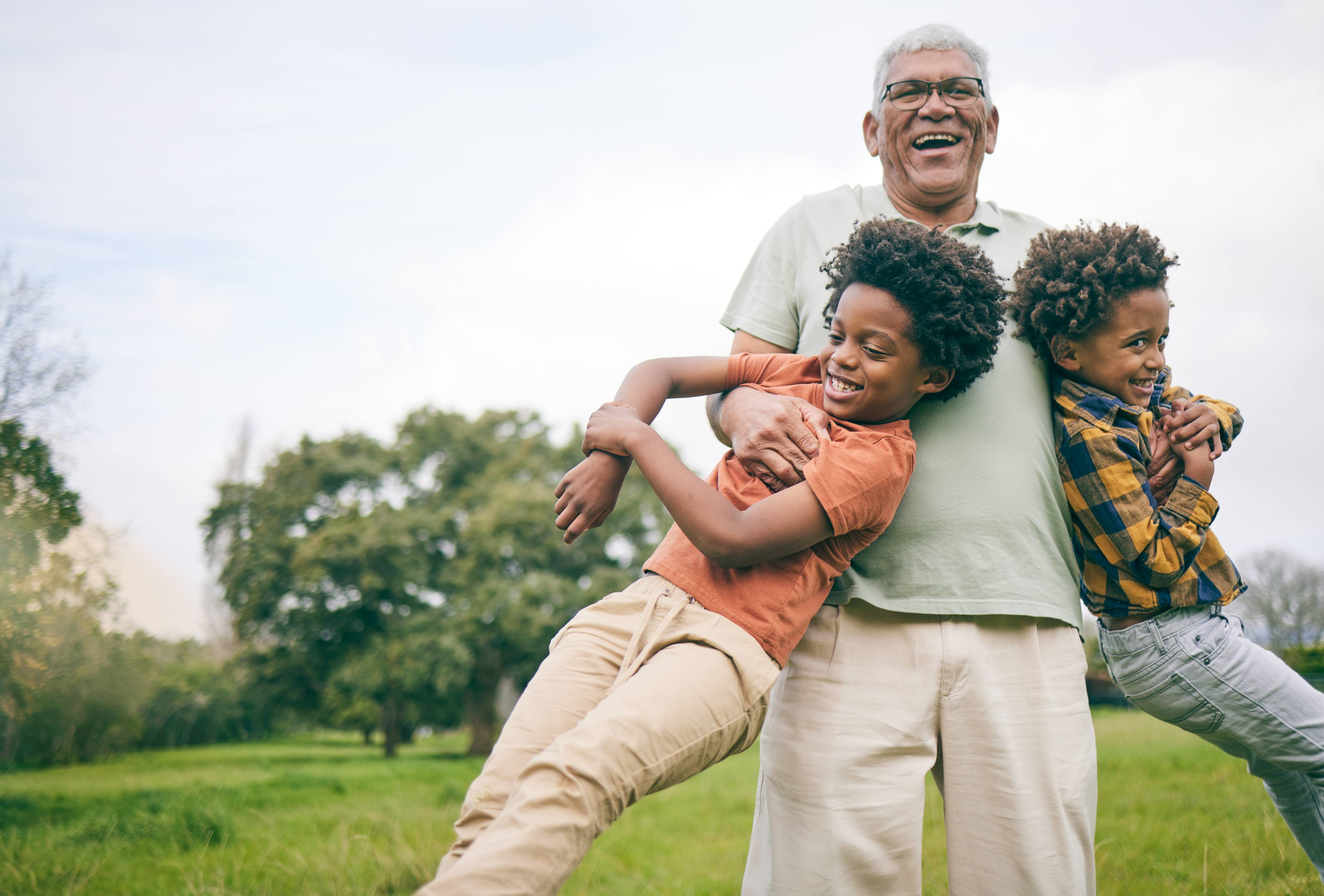 Grandfather playing with two grandchildren outdoors in park