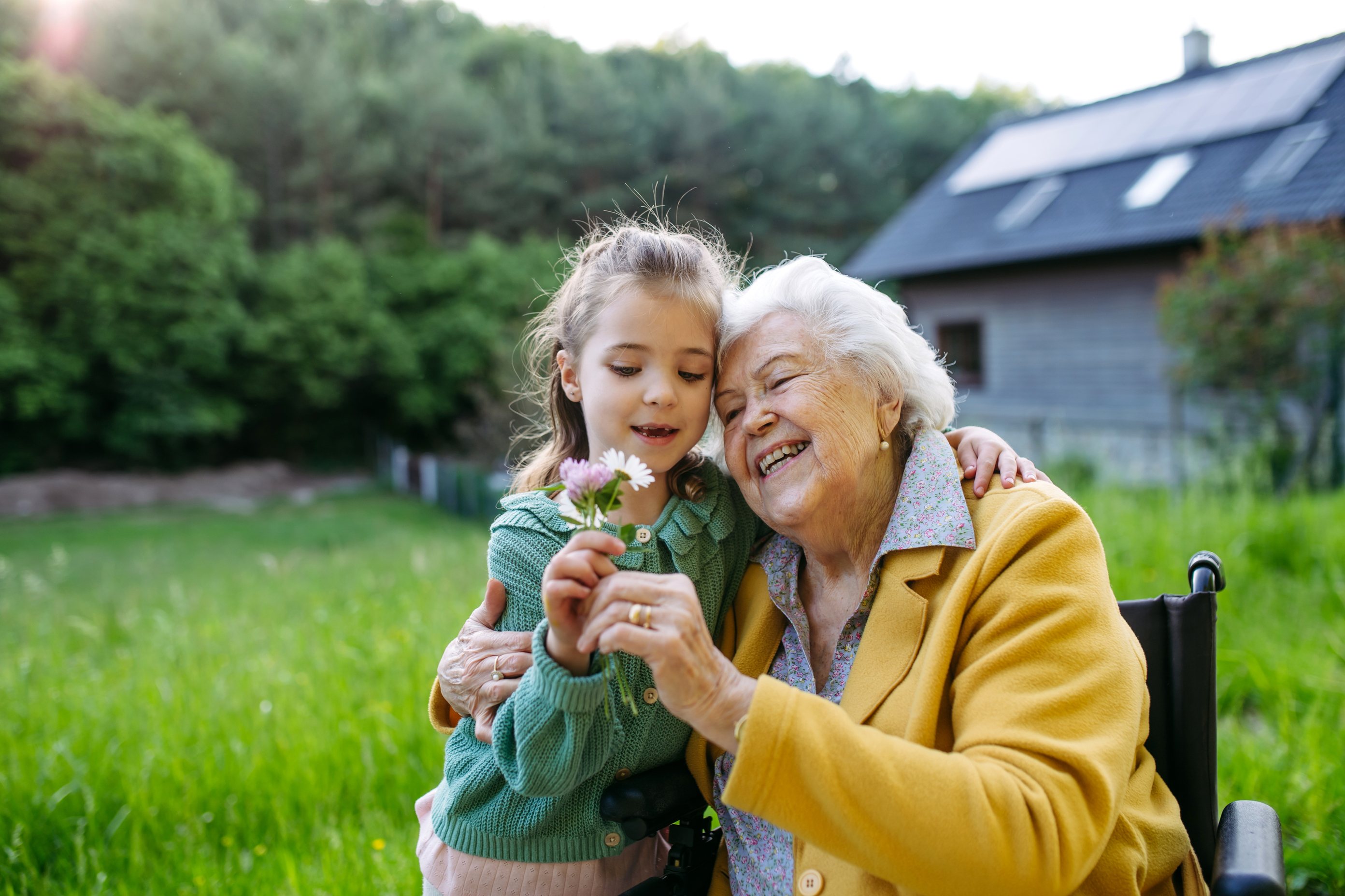 Grandmother and granddaughter sharing flower moment outdoors in garden