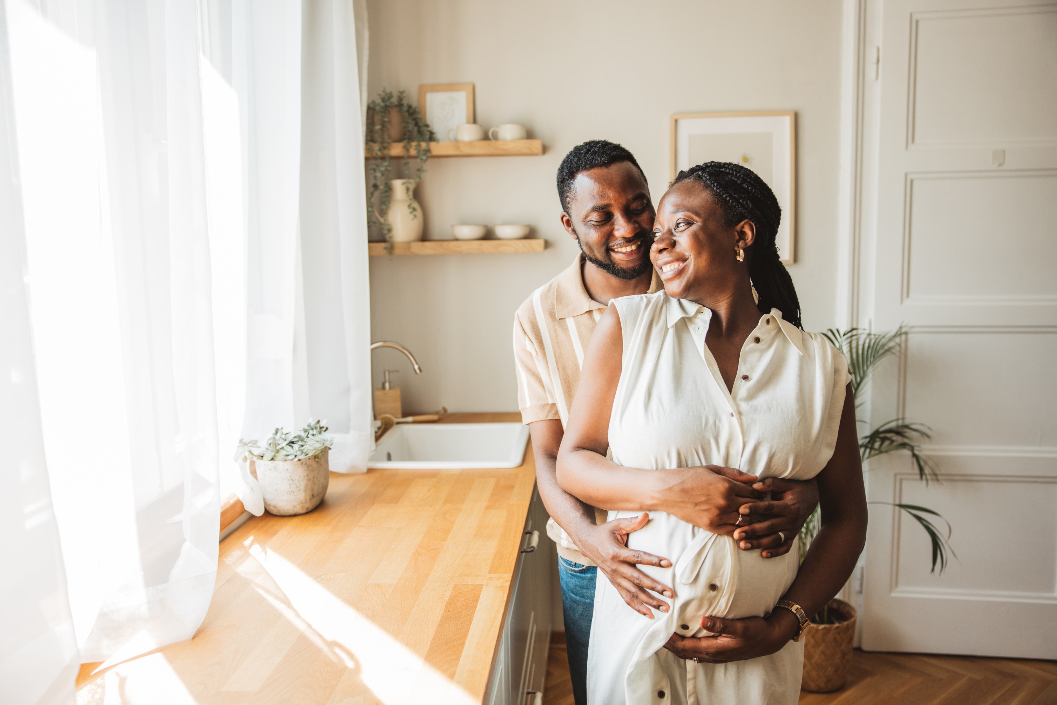 Happy couple embracing in bright modern kitchen with wooden countertops