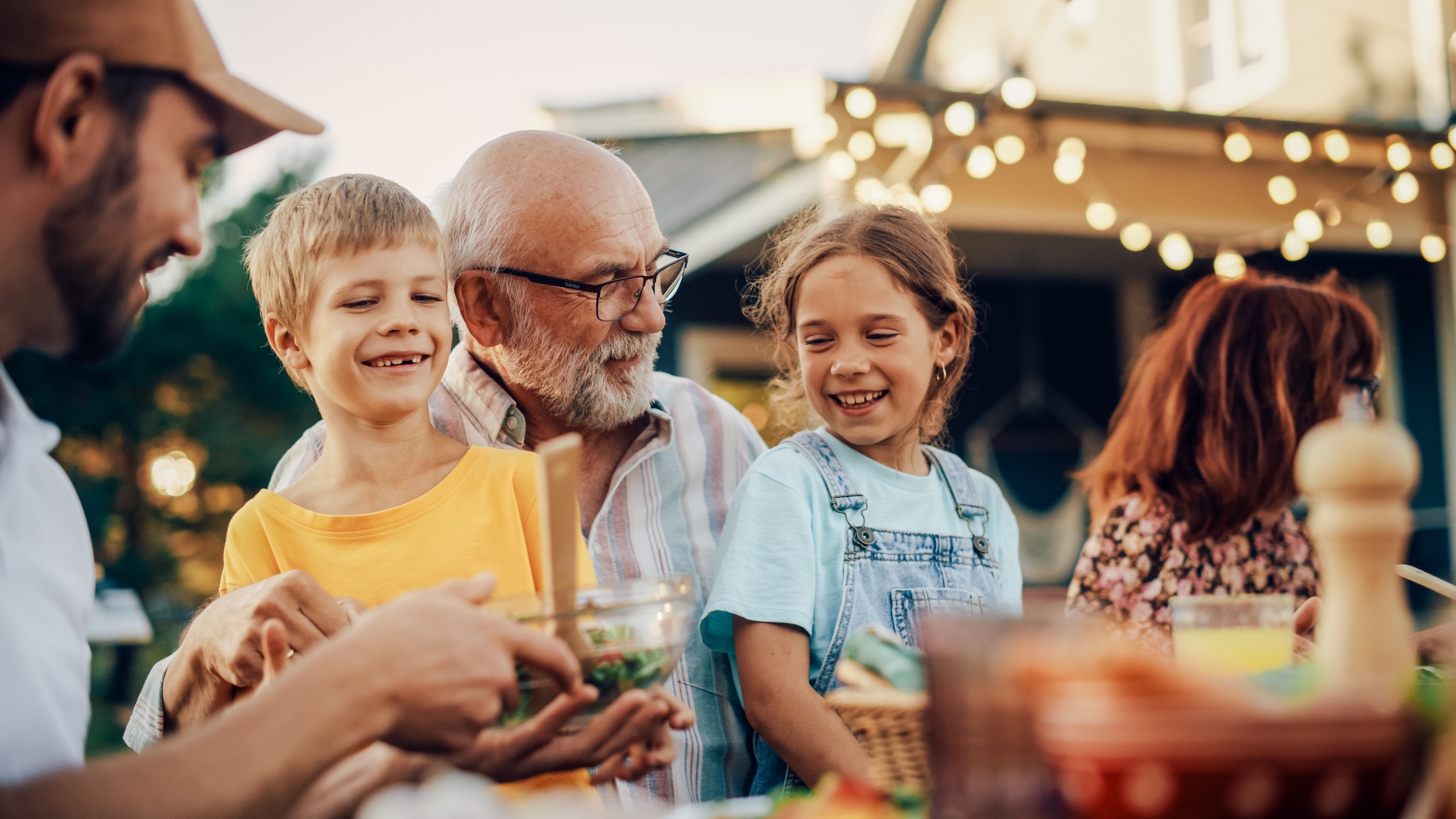 Happy family enjoying outdoor meal together with string lights