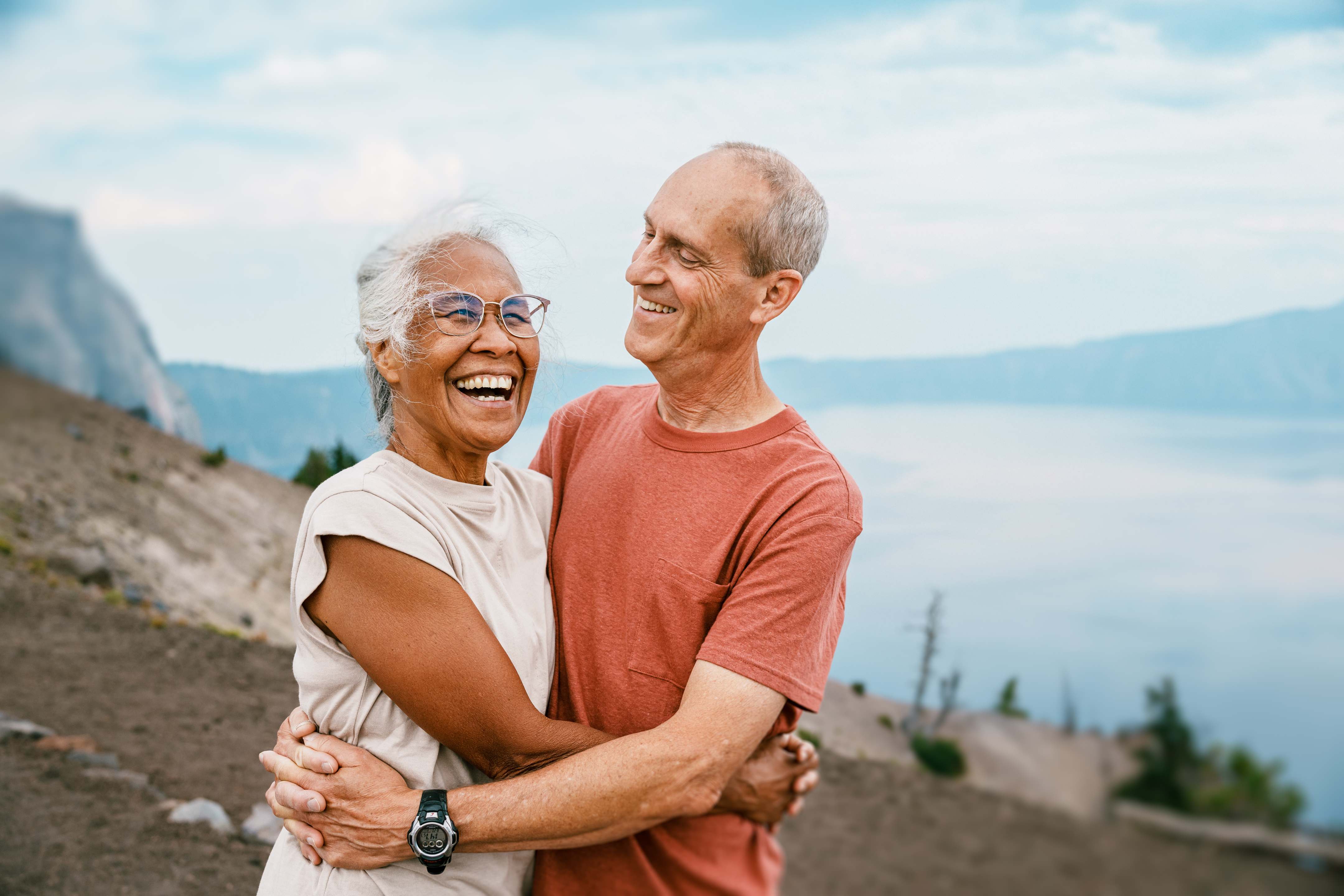 Happy senior couple embracing outdoors with mountain lake scenery