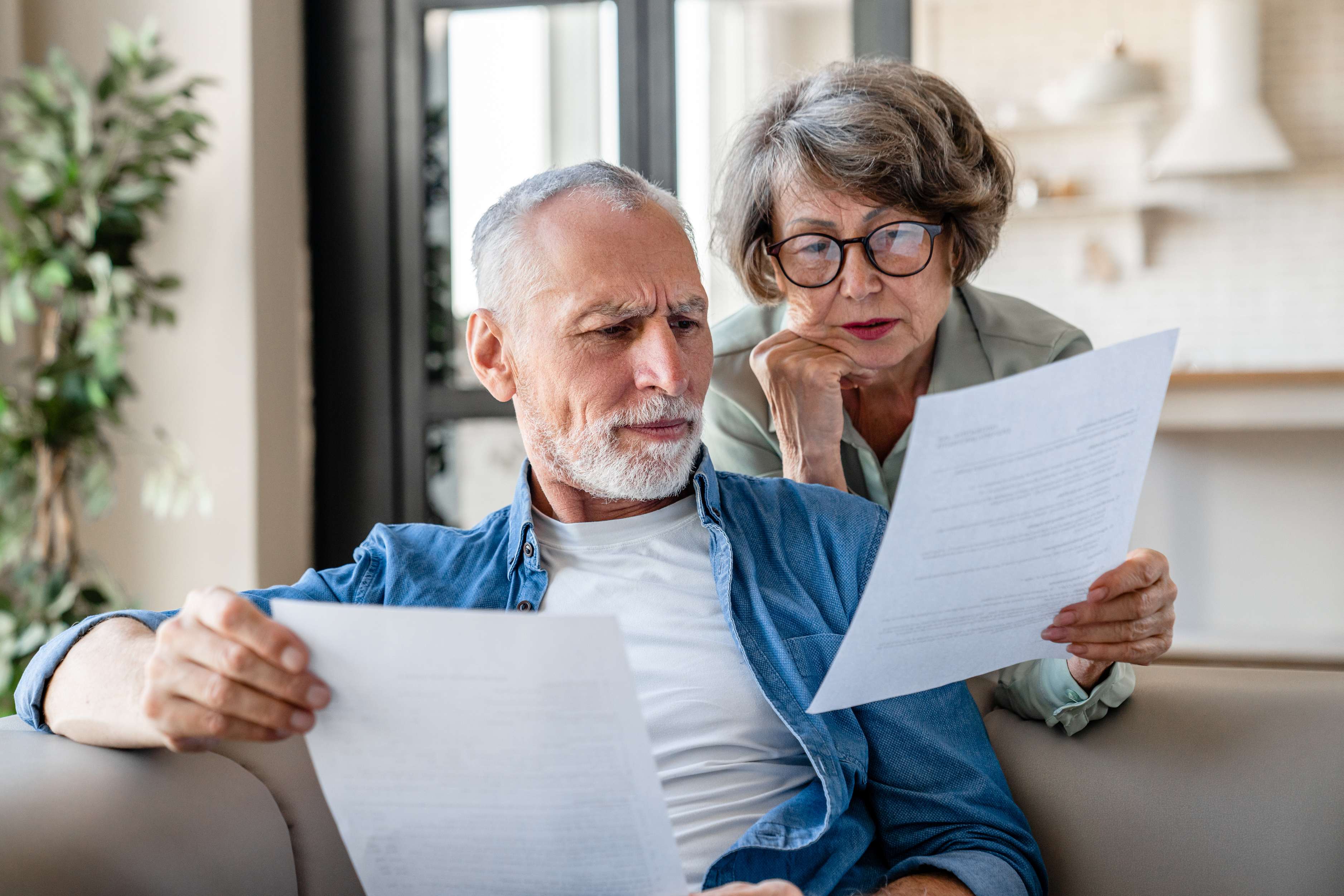 Senior couple reviewing documents together on couch at home