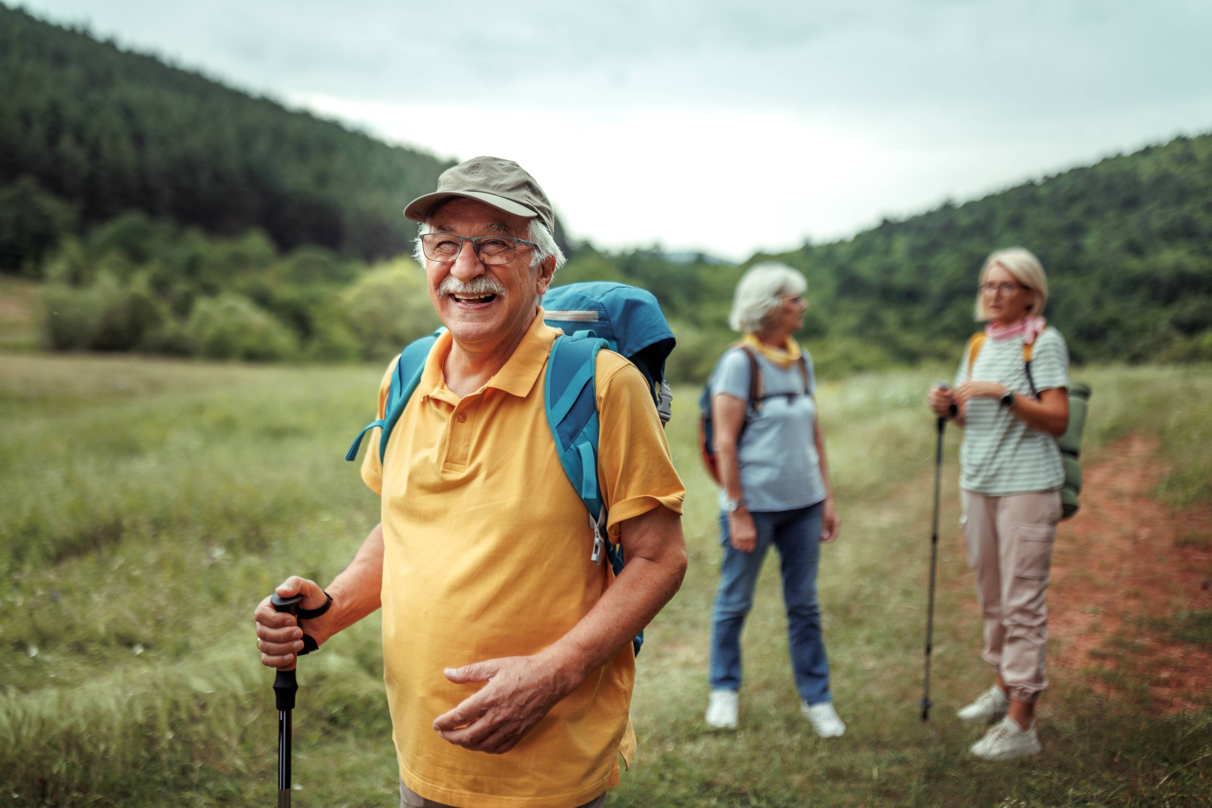 Senior hikers with backpacks and walking poles enjoying outdoor mountain trail