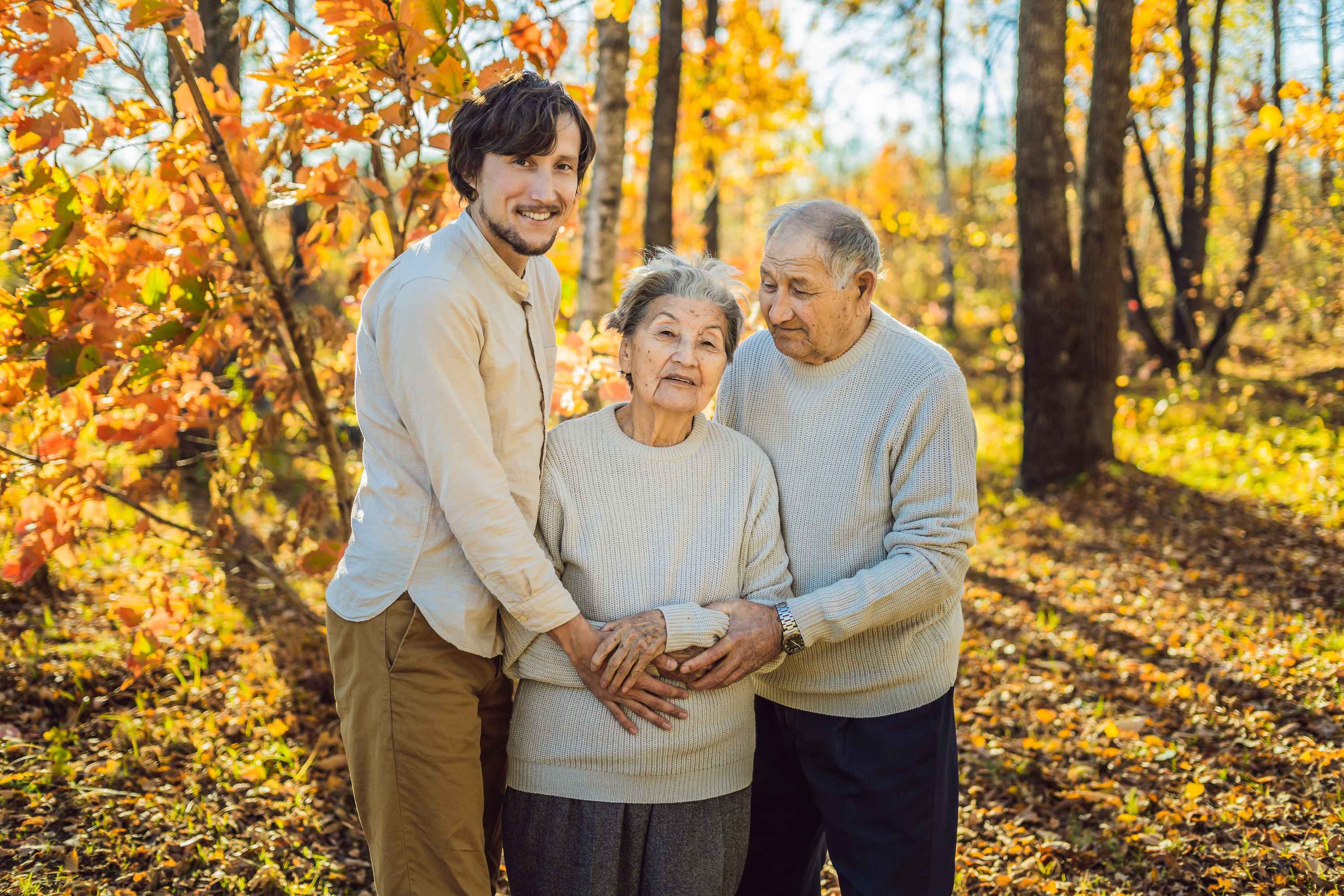Three generations family portrait in autumn forest with colorful fall foliage
