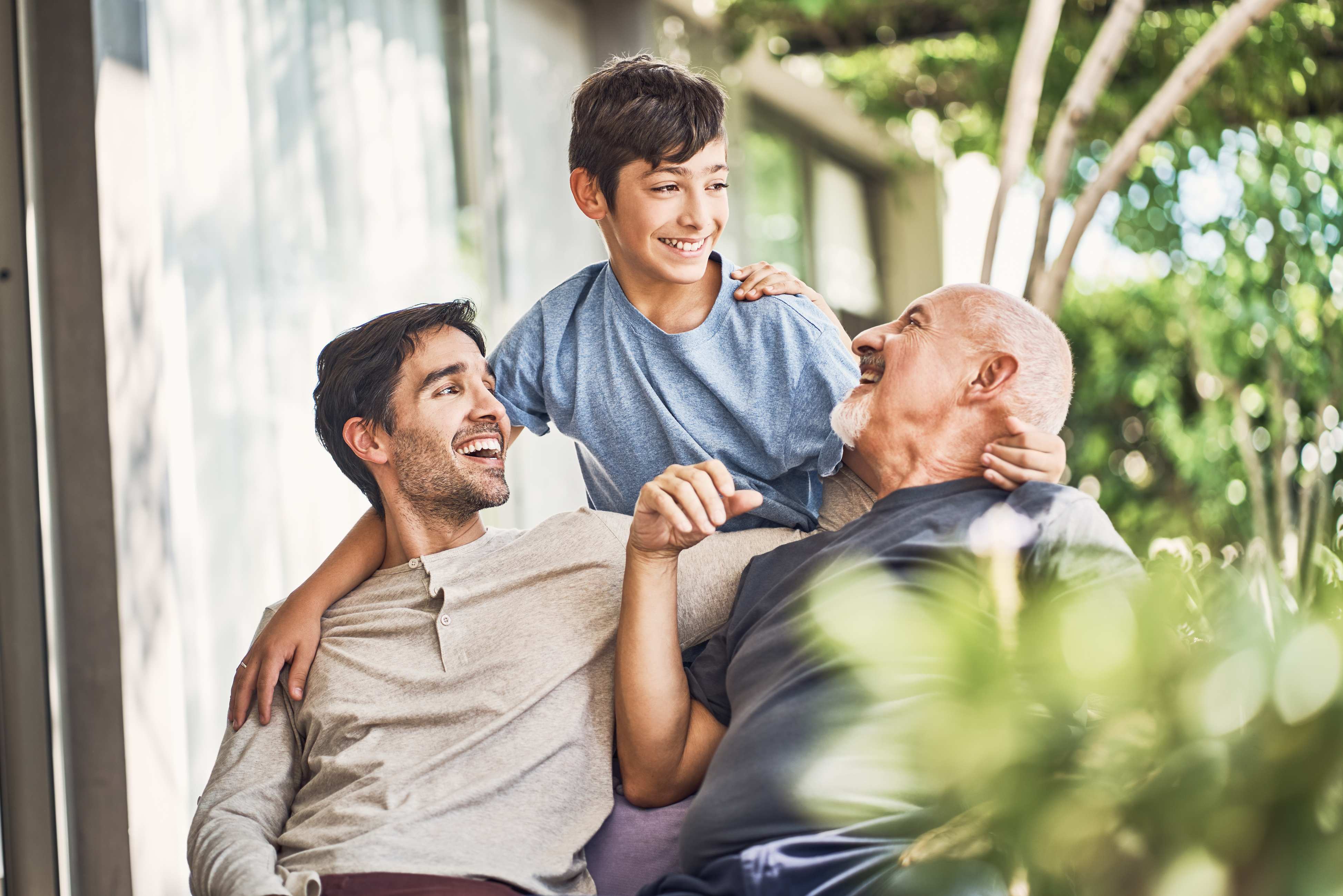Three generations of men laughing together outdoors in casual setting