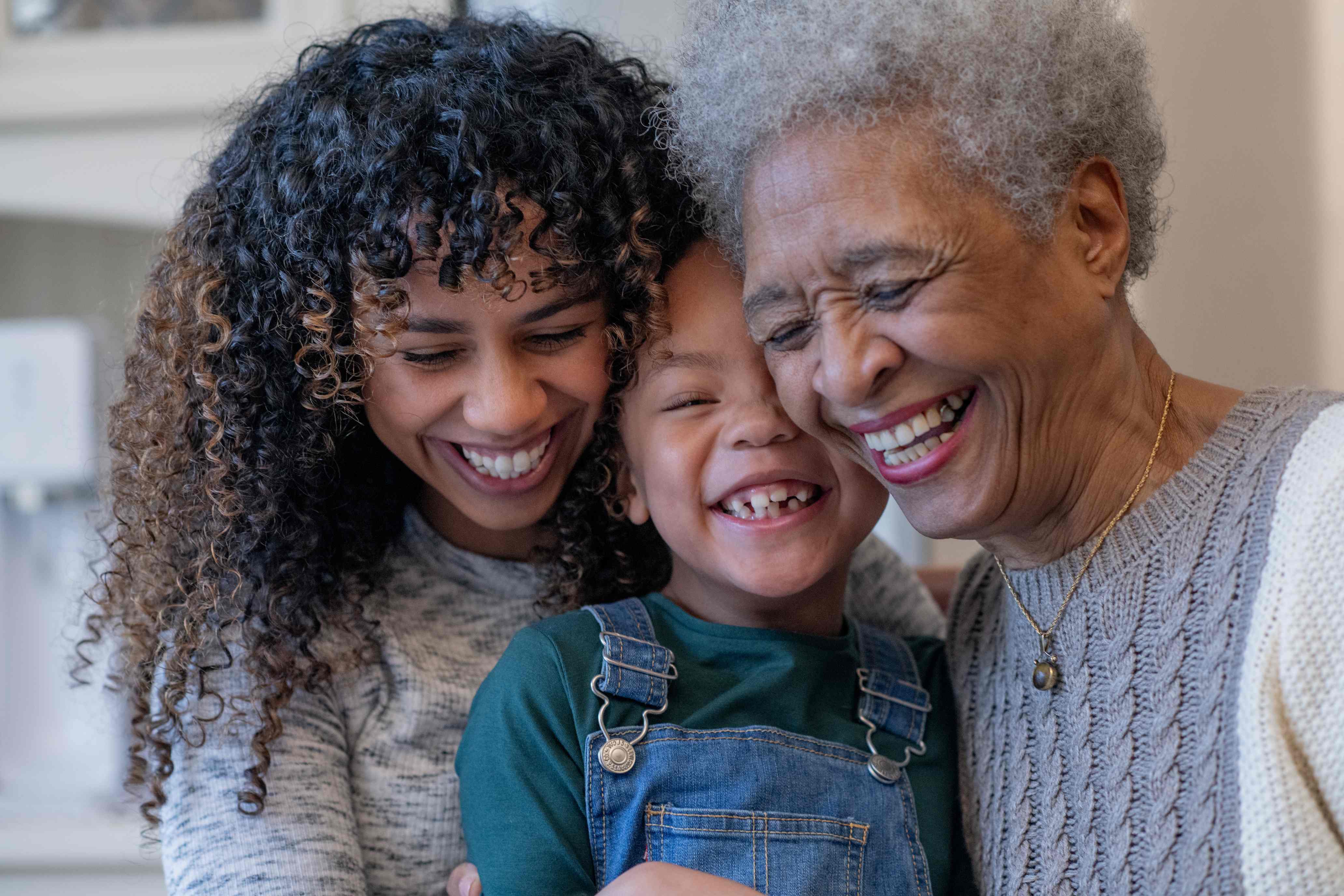 Three generations of women smiling together in warm family portrait