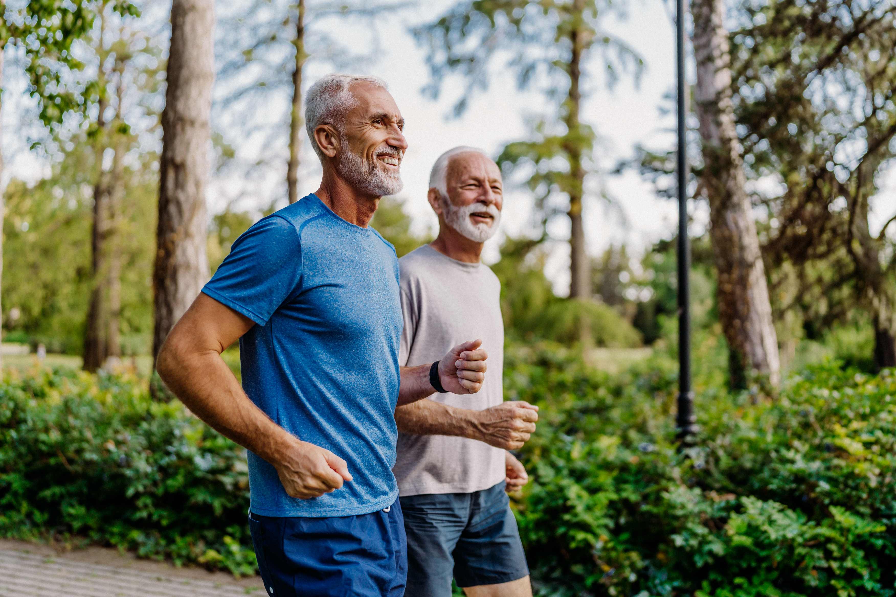 Two senior men jogging together in a park