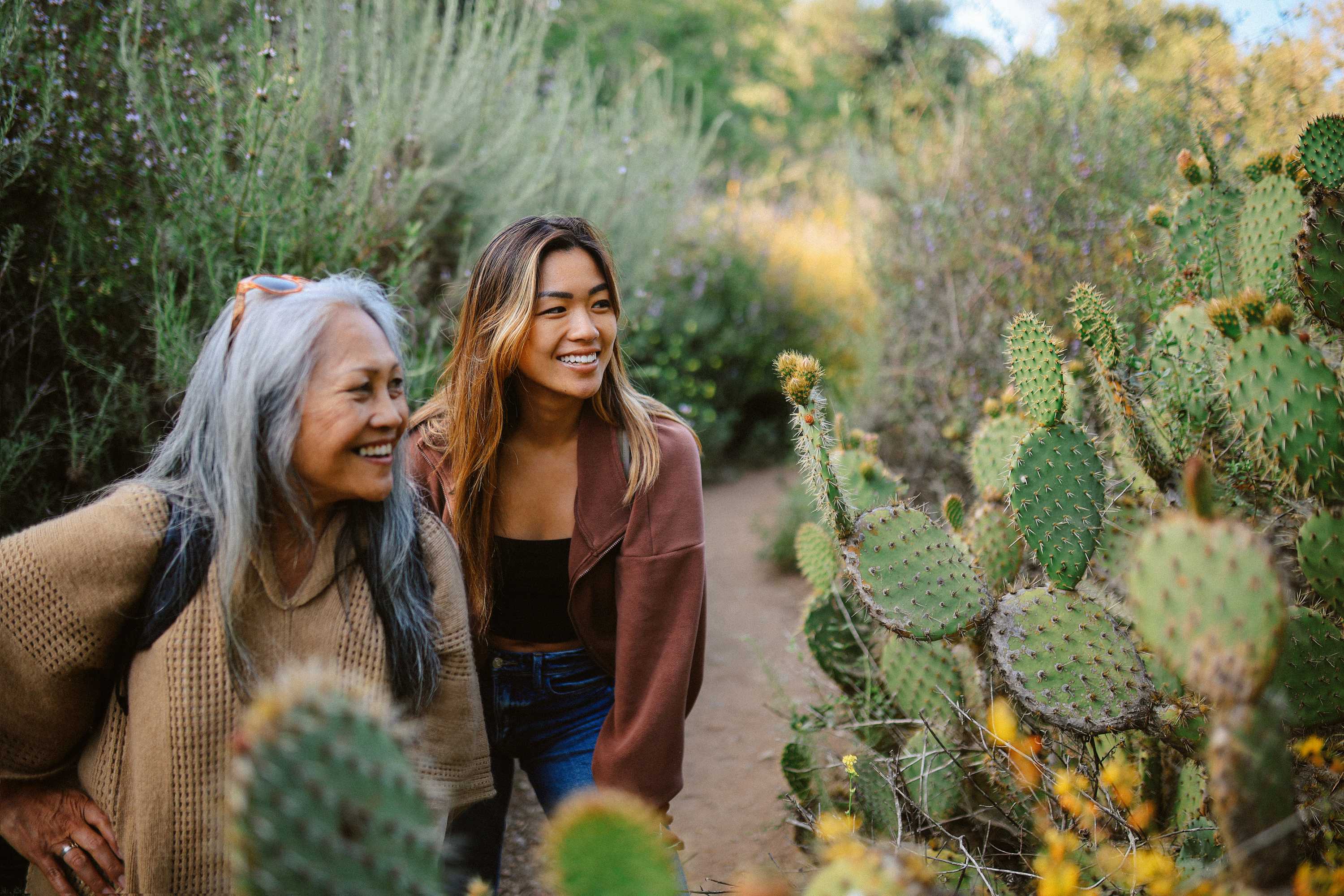 Two women smiling while walking through desert garden with cacti