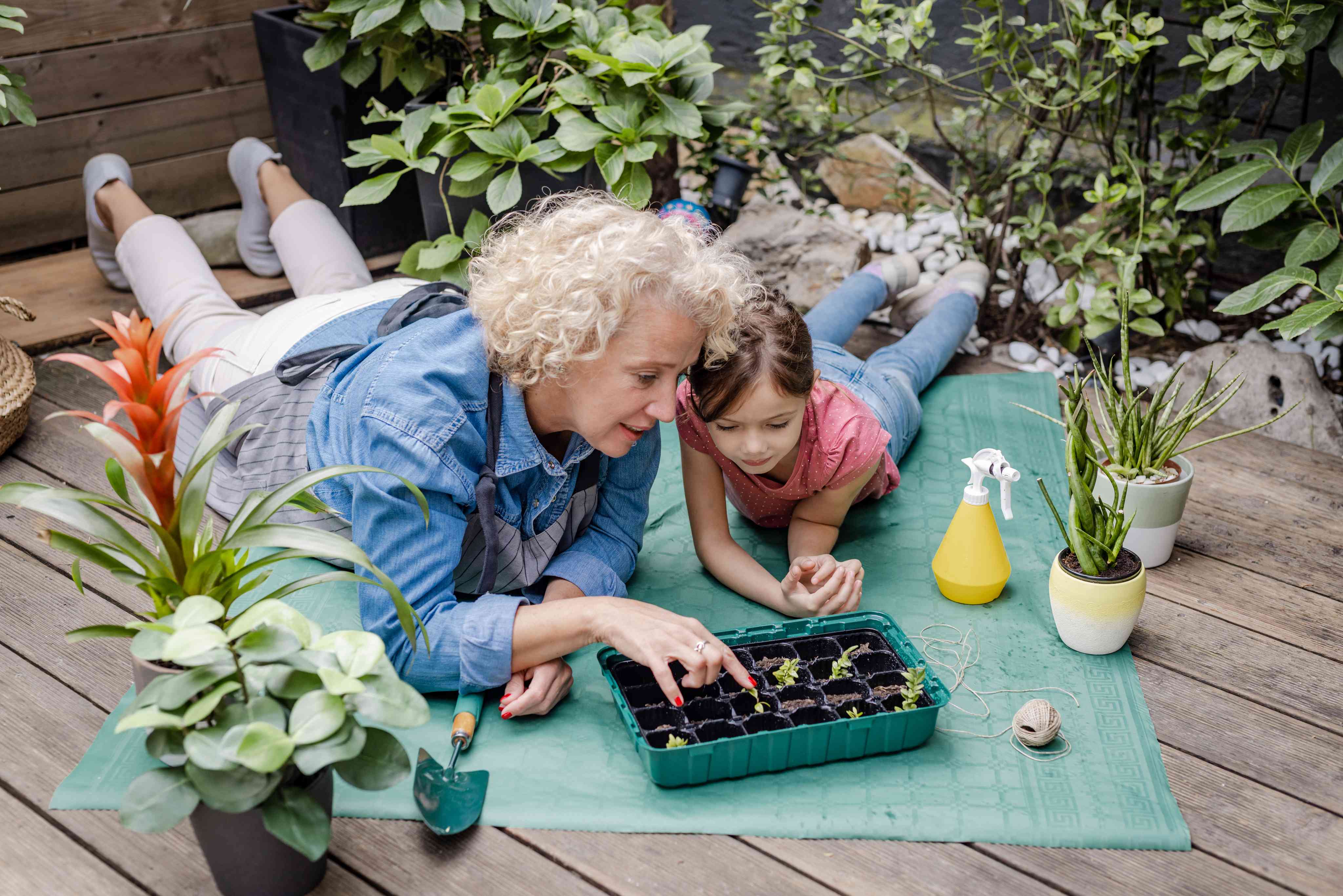 Woman and child gardening together on outdoor deck with plants