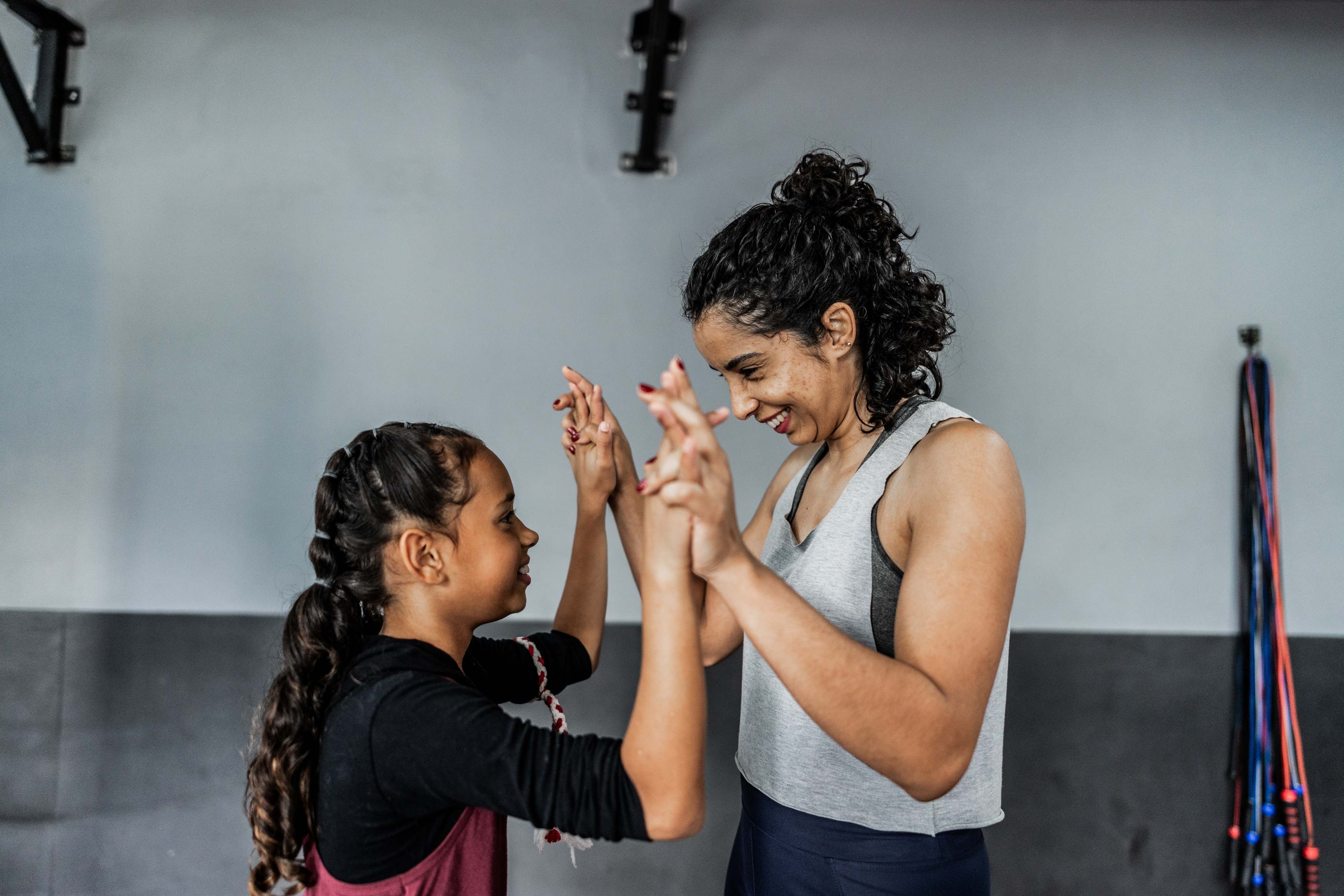 Woman and girl high-fiving in gym with exercise equipment