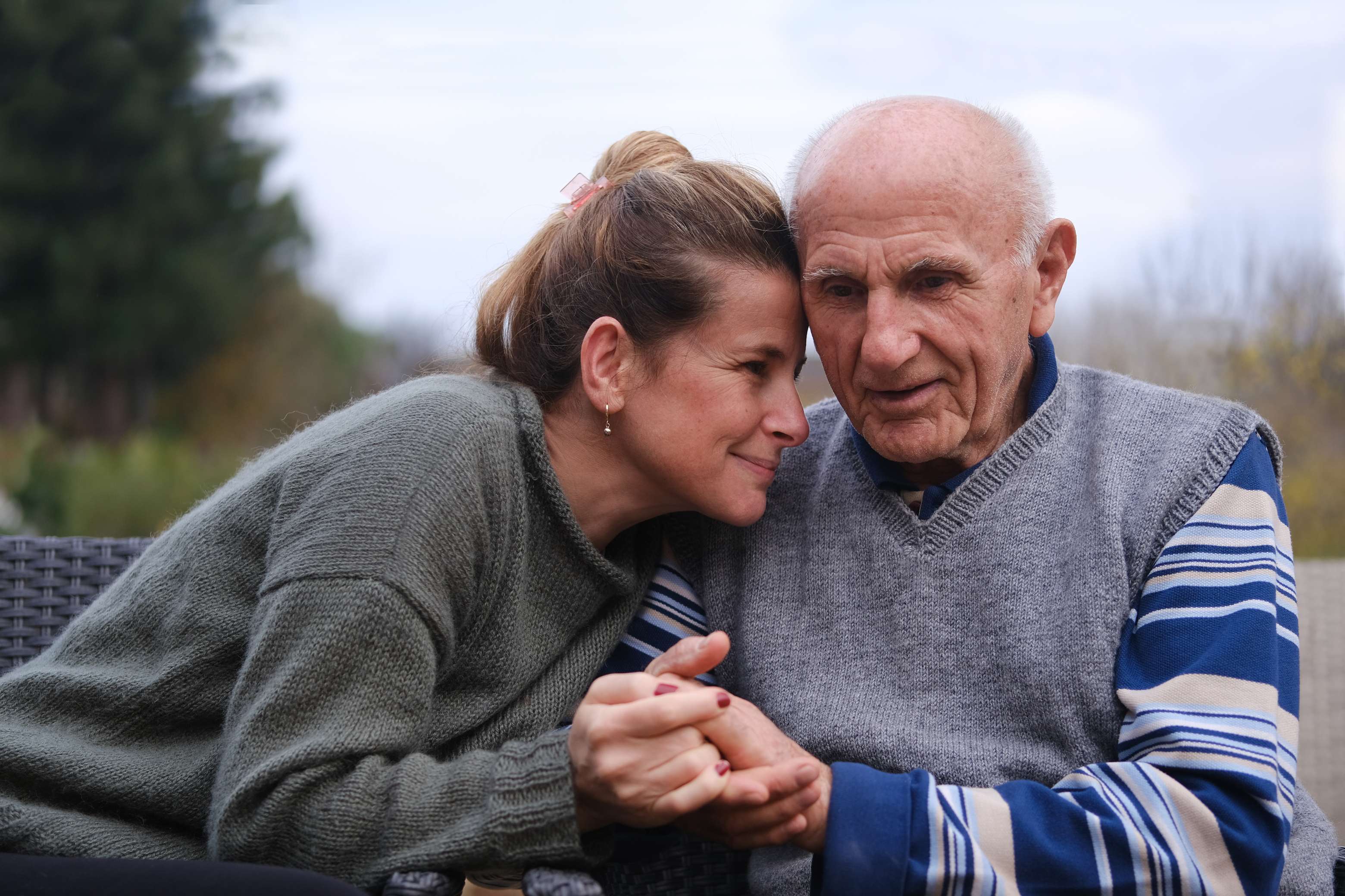 Young woman and elderly man embracing outdoors in warm moment